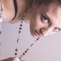 Color photo of a young woman clutching a rosary upside down.